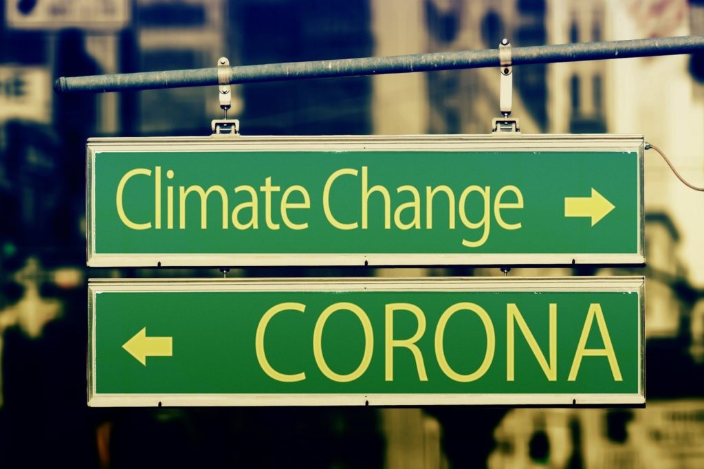 Green Sign that points to an arrow for climate change in one direction and corona in the other